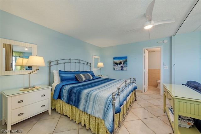 bedroom featuring light tile patterned flooring, a textured ceiling, ceiling fan, and connected bathroom