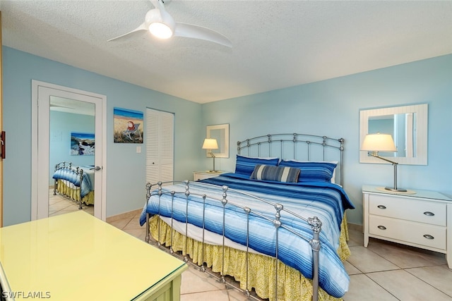 bedroom featuring light tile patterned floors, a closet, a textured ceiling, and ceiling fan