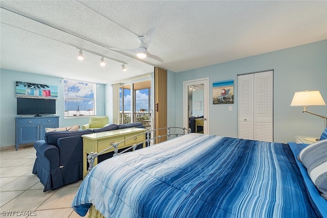 tiled bedroom featuring a closet, ceiling fan, rail lighting, a textured ceiling, and access to exterior