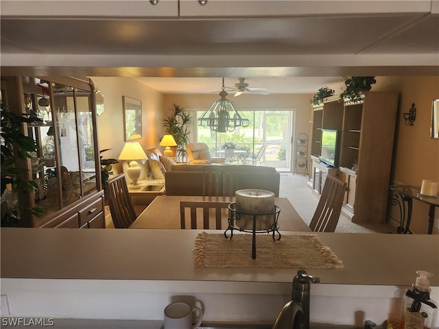 carpeted dining space with ceiling fan with notable chandelier