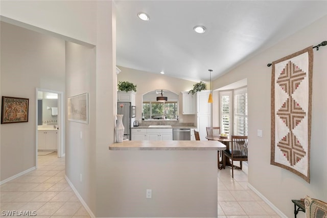 kitchen featuring kitchen peninsula, hanging light fixtures, vaulted ceiling, appliances with stainless steel finishes, and white cabinets