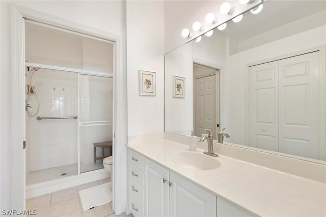 bathroom featuring toilet, a shower with door, tile patterned flooring, and vanity