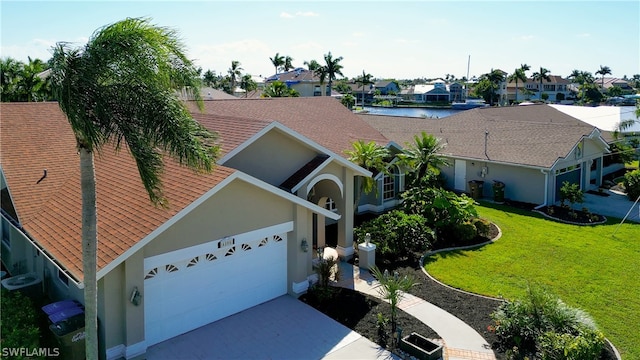 view of front of property featuring a front yard, a garage, and a water view