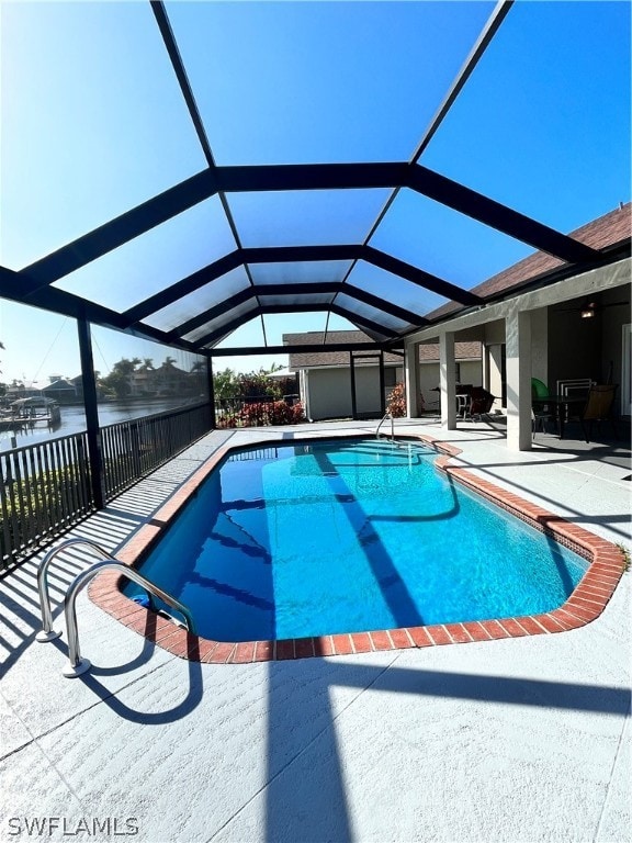 view of swimming pool featuring glass enclosure, a water view, and a patio