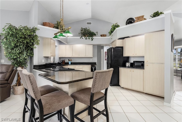 kitchen featuring kitchen peninsula, black fridge, cream cabinets, and light tile patterned flooring