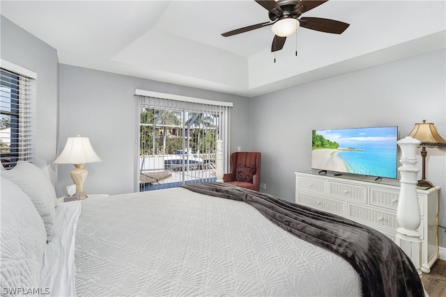 bedroom with hardwood / wood-style flooring, ceiling fan, a raised ceiling, and access to exterior