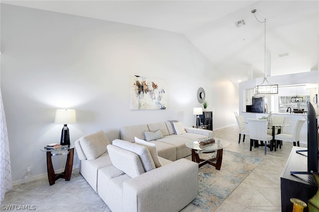 tiled living room featuring high vaulted ceiling and a notable chandelier