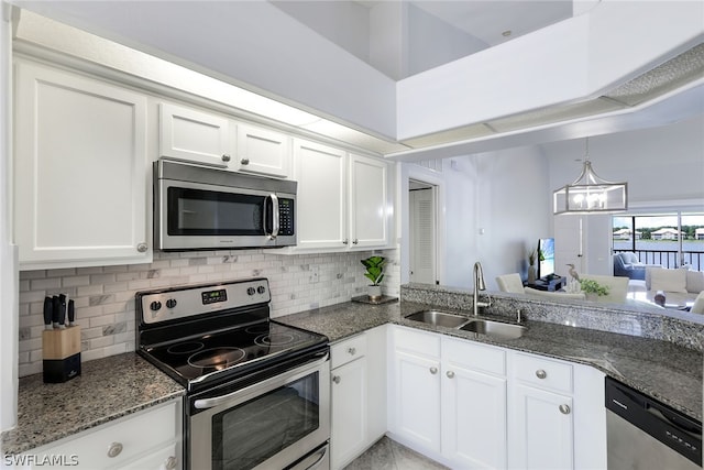 kitchen featuring appliances with stainless steel finishes, tasteful backsplash, dark stone counters, white cabinetry, and sink