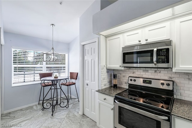 kitchen with dark stone counters, stainless steel appliances, white cabinets, and light tile flooring