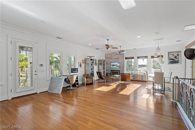 unfurnished living room with ceiling fan, plenty of natural light, crown molding, and light hardwood / wood-style flooring