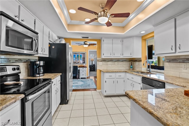 kitchen with decorative backsplash, stainless steel appliances, a tray ceiling, and ceiling fan