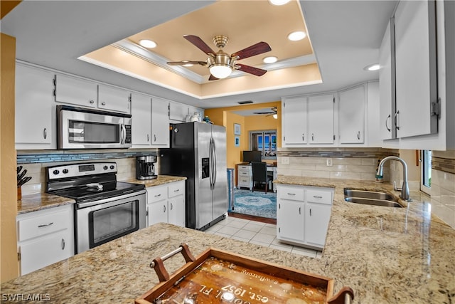 kitchen featuring stainless steel appliances, sink, decorative backsplash, ceiling fan, and a raised ceiling