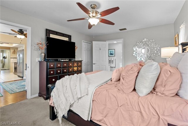 bedroom with light wood-type flooring, stainless steel refrigerator with ice dispenser, and ceiling fan