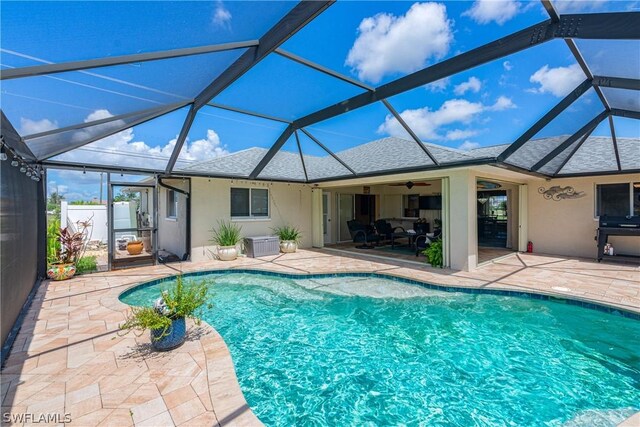 view of swimming pool with glass enclosure, a patio area, and ceiling fan