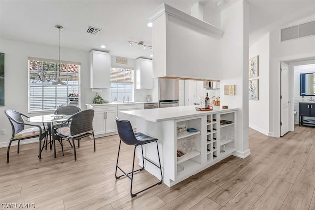 kitchen featuring track lighting, white cabinetry, pendant lighting, light wood-type flooring, and a breakfast bar