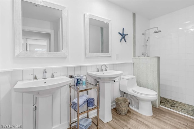 bathroom with tiled shower, tile walls, sink, tasteful backsplash, and toilet