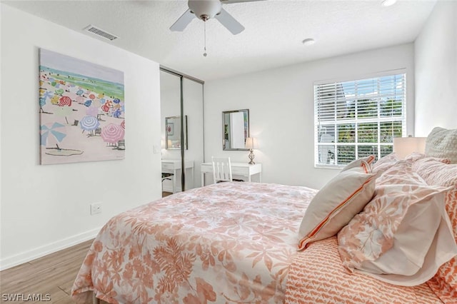 bedroom with hardwood / wood-style floors, a closet, ceiling fan, and a textured ceiling