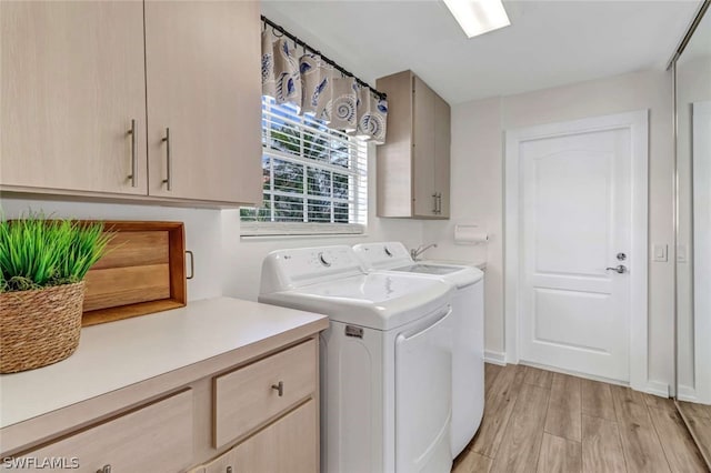 washroom with cabinets, independent washer and dryer, and light wood-type flooring