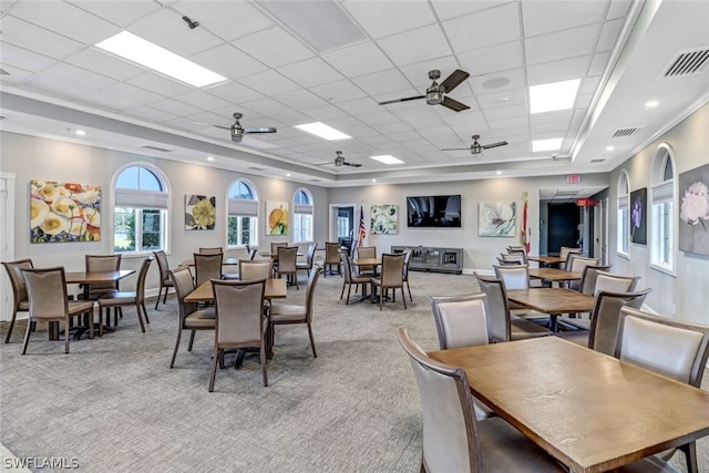 carpeted dining room featuring a drop ceiling, ceiling fan, and a tray ceiling