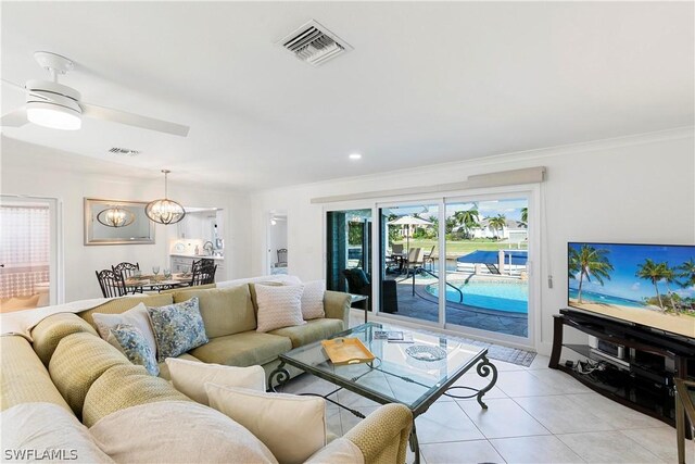 living room with ceiling fan with notable chandelier, ornamental molding, and light tile floors