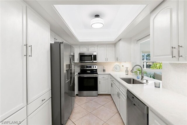 kitchen with sink, a raised ceiling, stainless steel appliances, and white cabinetry