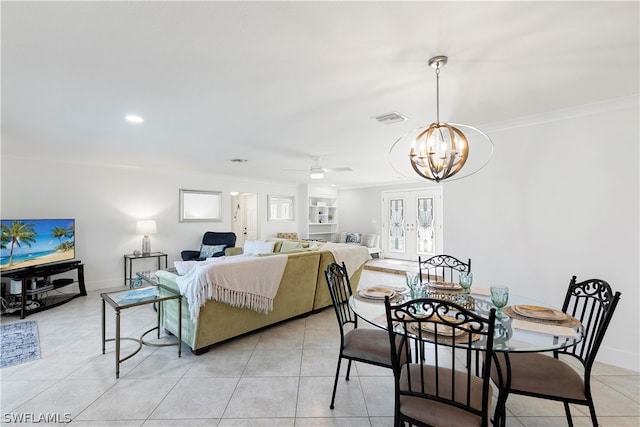 tiled dining room with ceiling fan with notable chandelier and crown molding