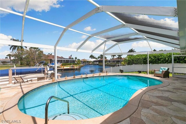 view of swimming pool featuring a patio, glass enclosure, and a water view