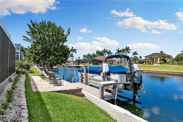 dock area featuring glass enclosure, a patio, boat lift, a water view, and a yard