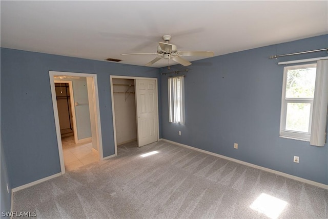 unfurnished bedroom with a closet, light colored carpet, and ceiling fan