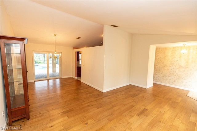 empty room with an inviting chandelier, lofted ceiling, and light wood-type flooring