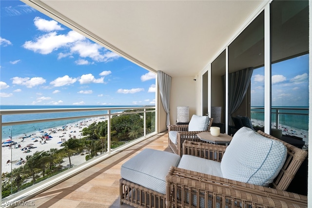 balcony featuring a view of the beach and a water view