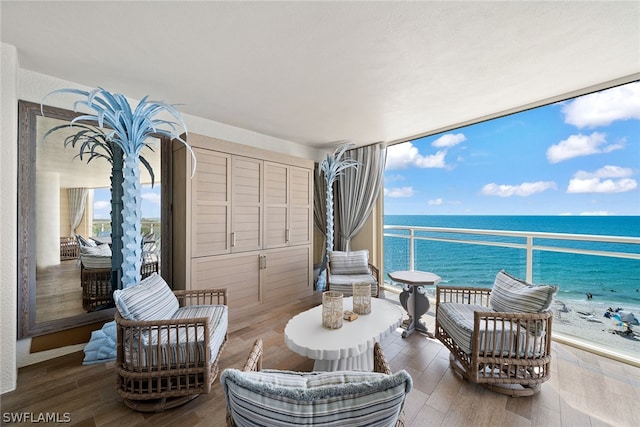 interior space featuring hardwood / wood-style floors, a water view, and a view of the beach