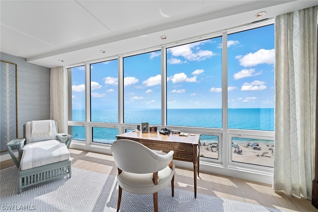 office area with hardwood / wood-style floors and a water view