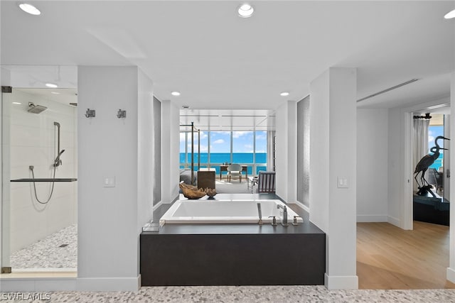 bathroom with wood-type flooring, a water view, and separate shower and tub