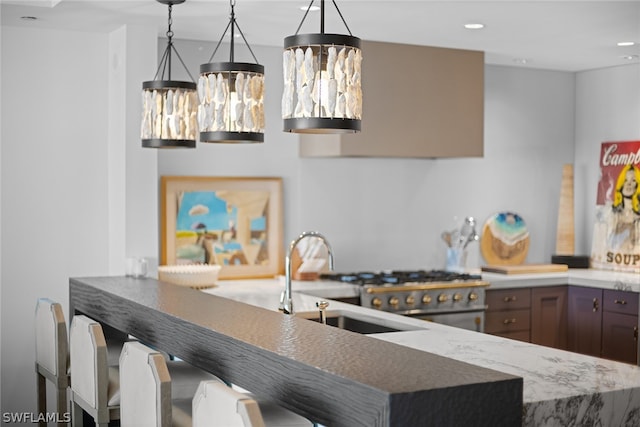 kitchen with a kitchen bar, sink, decorative light fixtures, and range