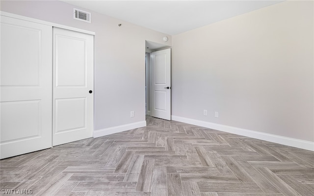 unfurnished bedroom with light parquet floors and a closet