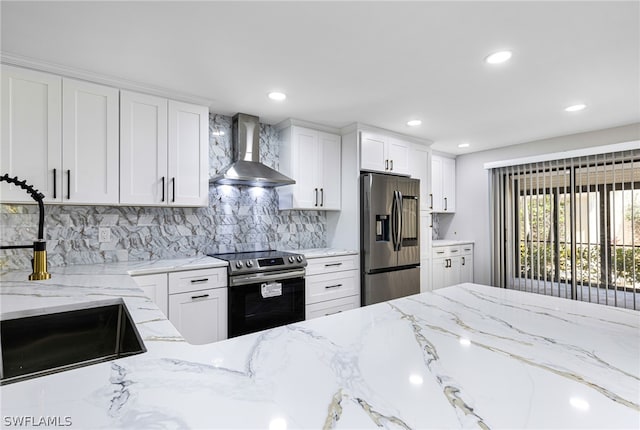 kitchen featuring wall chimney exhaust hood, light stone countertops, white cabinetry, appliances with stainless steel finishes, and tasteful backsplash