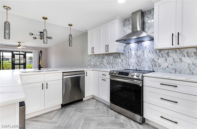 kitchen featuring light parquet floors, backsplash, stainless steel appliances, ceiling fan, and wall chimney exhaust hood