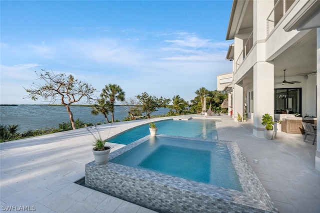 view of pool featuring an in ground hot tub, a water view, a patio, and ceiling fan