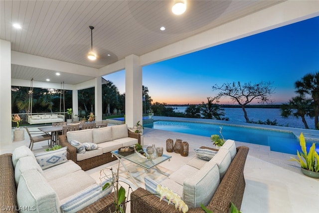 patio terrace at dusk featuring a water view and an outdoor hangout area