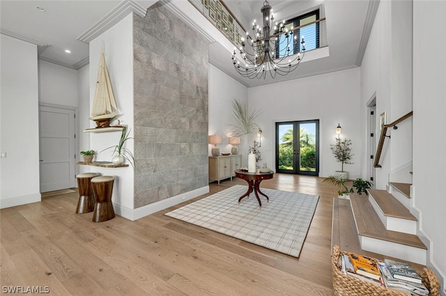 entryway featuring french doors, a chandelier, a high ceiling, and ornamental molding