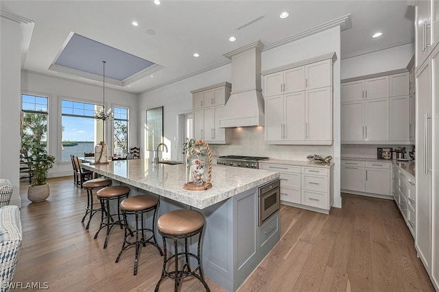 kitchen featuring pendant lighting, premium range hood, a spacious island, built in microwave, and a breakfast bar area