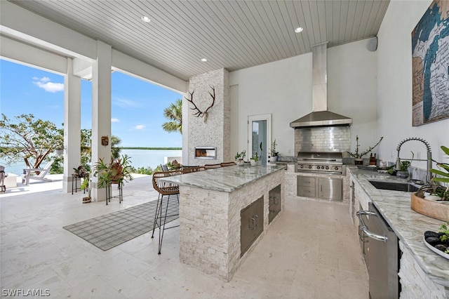 view of patio featuring an outdoor kitchen, area for grilling, a water view, and an outdoor wet bar