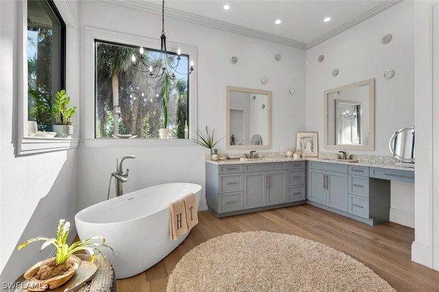 bathroom featuring a bath, vanity, hardwood / wood-style flooring, and crown molding