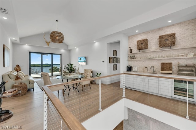 dining area featuring light wood-type flooring, sink, and vaulted ceiling