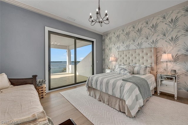 bedroom featuring a water view, light hardwood / wood-style flooring, access to exterior, ornamental molding, and a chandelier