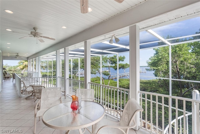 sunroom featuring ceiling fan, a healthy amount of sunlight, and a water view