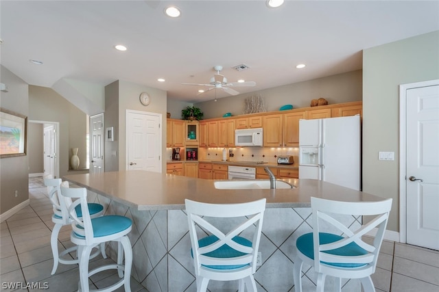 kitchen featuring white appliances, a large island, a breakfast bar, ceiling fan, and light tile floors