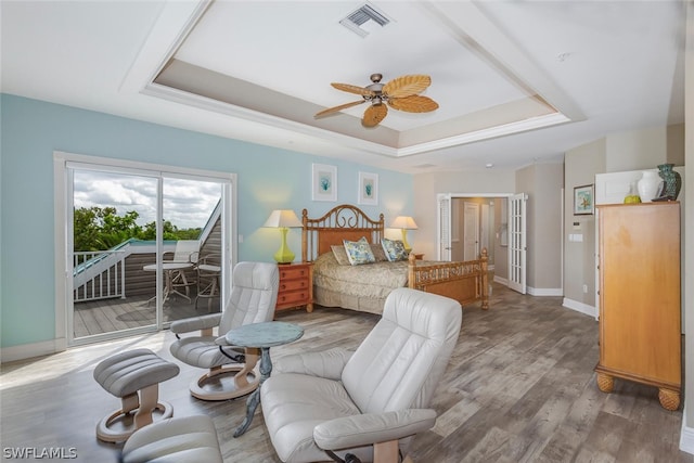 bedroom featuring a tray ceiling, hardwood / wood-style flooring, ceiling fan, and access to exterior