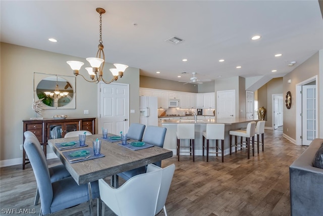 dining room with hardwood / wood-style floors, sink, and ceiling fan with notable chandelier